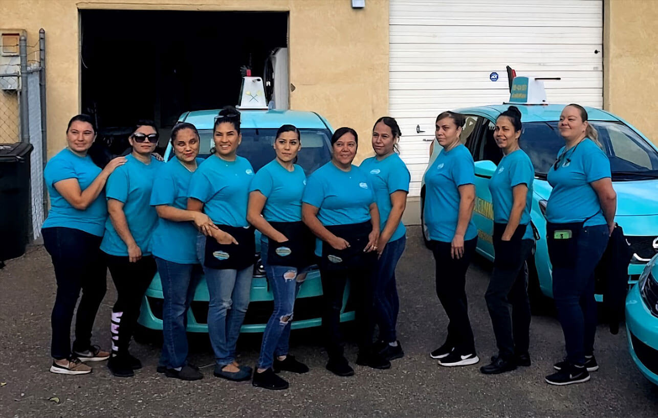 A group of Texas maids standing in front of a blue car.