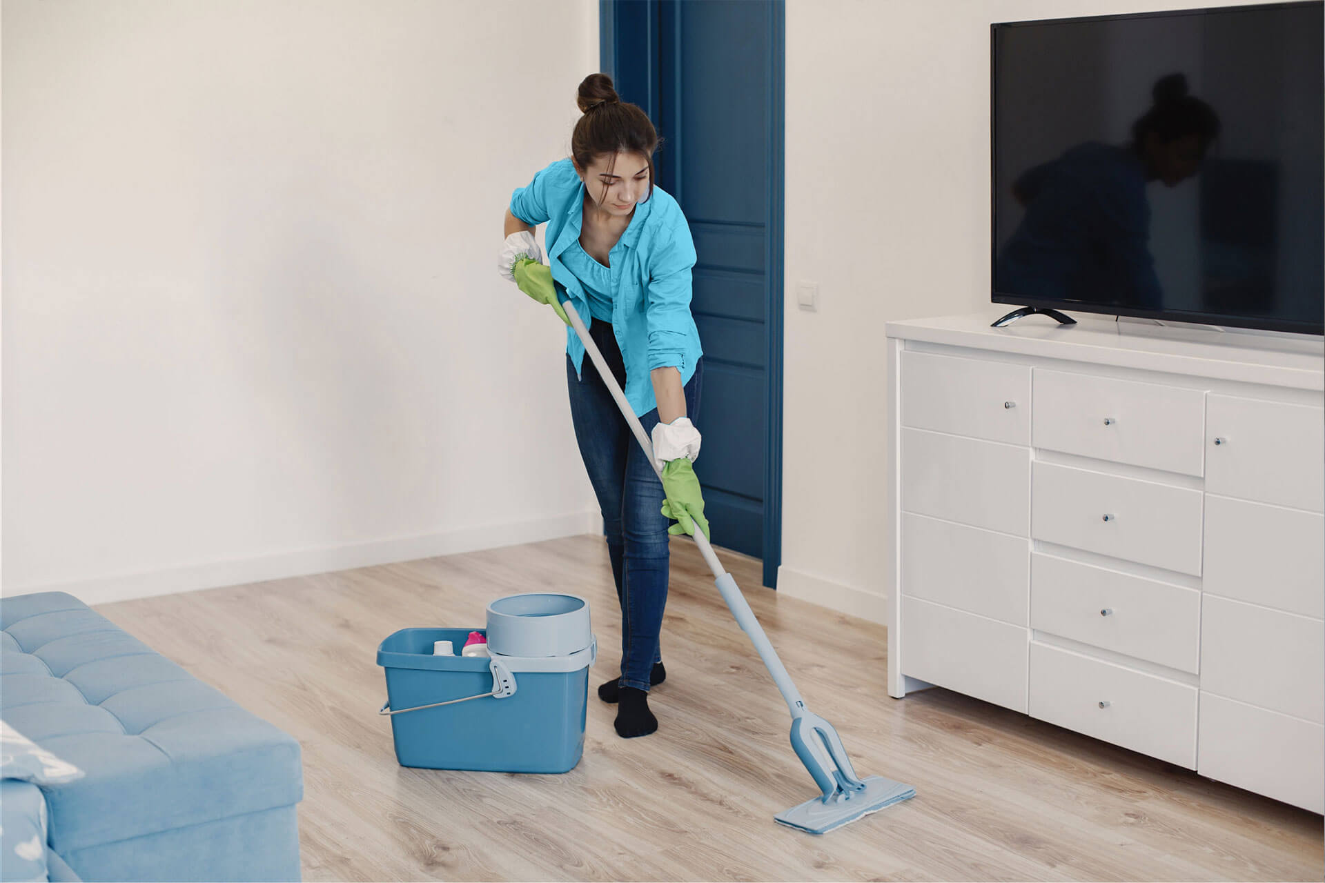 A maid from Texas cleans a living room with a mop